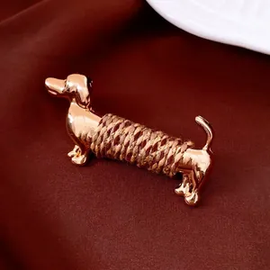Detailed macro view of a golden dachshund brooch with brown rope wrap on silk background