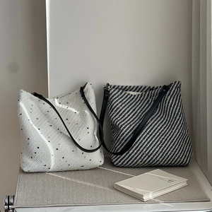 Detail of wool tweed tote bags showing colorful speckle texture and black leather straps