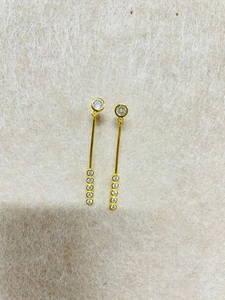 Gros plan de boucles d'oreilles pendantes dorées avec pierres sur tissu beige
