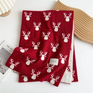 Close-up of red and white knitted winter scarf with festive Christmas reindeer patterns