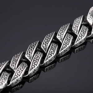 Detailed view of silver stainless steel chain bracelet with Greek key pattern engraving