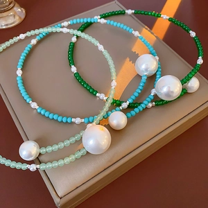 Three-layer beaded pearl necklaces in shades of green on a golden jewelry box