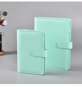 Two mint green leather A5 A6 journals in different sizes with snap closure on grey desk