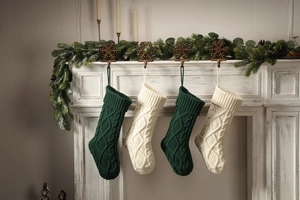 Close-up of knit Christmas stockings with cable pattern hanging on a white fireplace