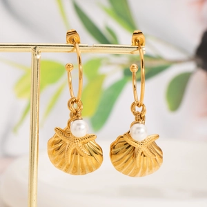 Detail of gold shell earrings featuring starfish relief and elegant hanging white pearls