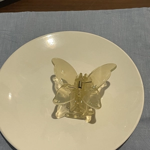 Detail view of a yellow translucent butterfly hair claw clip with golden metal spring