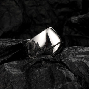 Macro detail of a silver twisted C-shape wide metal ring on a textured black backdrop