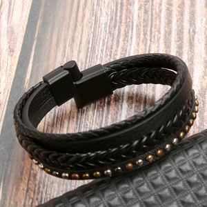 Close-up of multilayer braided leather bracelet with metallic rivets and magnetic clasp