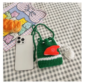 Detail of forest green crochet reindeer bag with red Christmas hat on checkered cloth