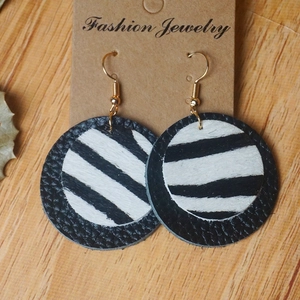 Détail de boucles d'oreilles rondes double couche en cuir noir et imprimé zèbre