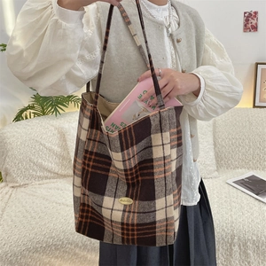 Close-up of vintage plaid wool tote bag with brown checkered pattern and metal logo