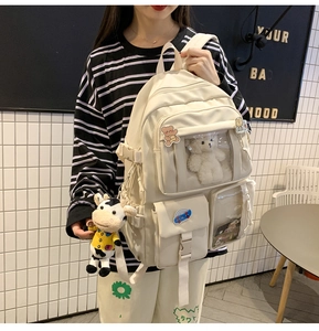 Vista dettagliata dello zaino in tela crema con tasche e accessorio orsetto di peluche