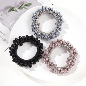 Three minimalist faux pearl elastic hair ties in black, grey, and pink on a white plate
