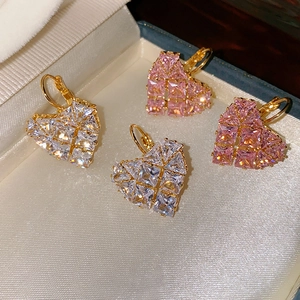 Vue macro de boucles d'oreilles en cœur avec zircons roses et clairs dans un coffret