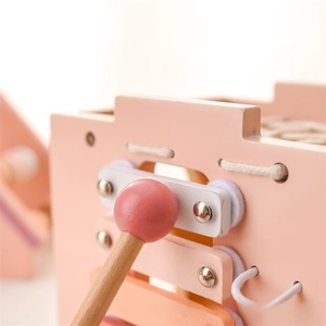 Macro detail of smooth wooden xylophone keys and mallet in soft pink and white tones
