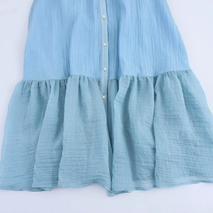 Elegant light blue sleeveless shirt dress with button-down front and ruffled hem details