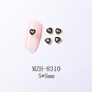 Close-up of 5x5mm heart nail charms with gold borders and black enamel finish