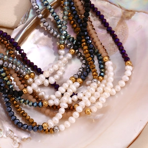 Detail of handmade beaded necklace with freshwater pearls and faceted crystals on a shell