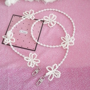 Detail of handmade pearl chain strap featuring white woven flower charms and silver clasps