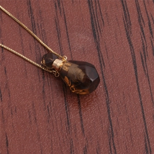 Macro view of flame-shaped brown crystal perfume bottle pendant with gold chain