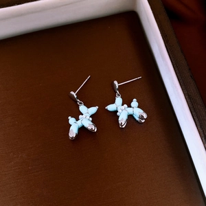 Détail de boucles d'oreilles chien ballon bleu clair avec accents argentés sur velours