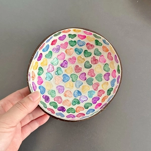 Detailed view of a handmade coconut shell bowl featuring colorful heart-shaped interior patterns