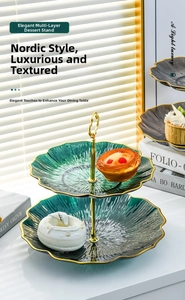 Detail of dark green glass tiered dessert stand with gold trim and heart handle