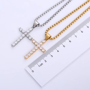 Macro view of gold and silver cross pendants with zircon inlay next to a ruler for scale