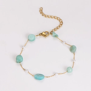 Detail of gold chain bracelet with green turquoise stones and white pearls on white background