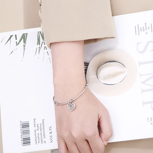 Minimalist silver stainless steel heart charm bracelet on model wrist with suit