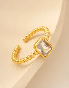 Dettaglio dell'anello dorato con zircone rettangolare e fascia con texture a palline