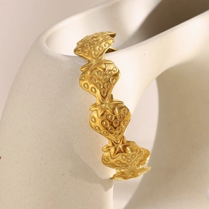 Detail shot of golden strawberry-shaped bracelet on minimalist geometric sculpture
