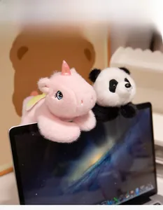 Plush panda and pink unicorn doll hanging on a laptop screen as cute decor