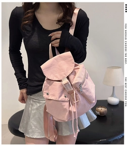 Detailed view of pink nylon backpack featuring flap cover and dual front pockets