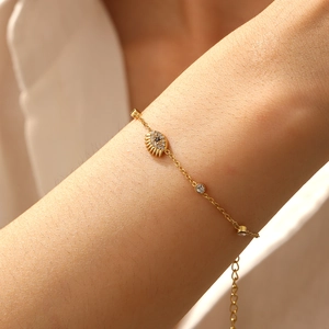 Macro shot of gold-plated evil eye bracelet with blue zircons and eyelash details on wrist