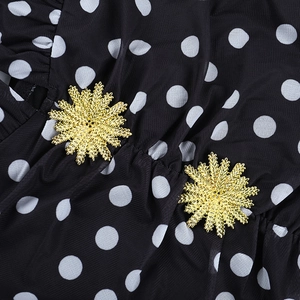 Details von schwarzem Polka-Dot-Netzstoff mit eleganten goldenen Schneeflocken-Knöpfen