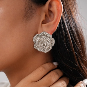 Gros plan d'une boucle d'oreille fleur argentée avec strass portées par un mannequin