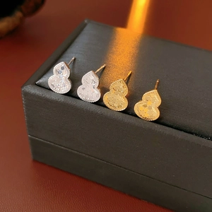 Macro shot of 18k gold and silver plated gourd earrings on a premium black jewelry box