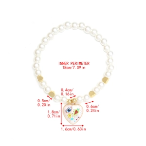 Detail view of pearl bracelet featuring golden heart beads and evil eye enamel pendant