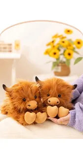 Detailed view of two brown Highland cow plush toys with long fur and heart-shaped feet