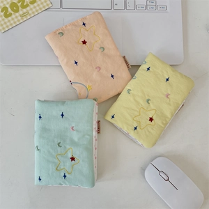 Detailed view of quilted fabric passport holders with star embroidery in pastel colors