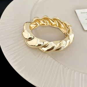 Detailaufnahme des goldenen gedrehten Armreifs mit Hochglanzfinish und Scharnierverschluss