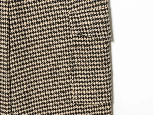 Detailed view of houndstooth pattern and pocket stitching on beige work pants