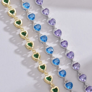 Detailed macro view of heart-shaped zircon bracelets in emerald green, blue, and purple