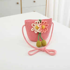 Close-up of pink straw bag with decorative 3D flowers and green pom-poms for girls