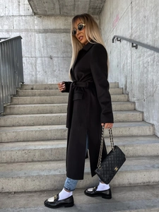 Outdoor shot of a black wool-blend long coat with lapel collar and waist tie detail