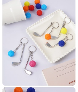 Close-up of mini golf club pendants with colorful balls on a decorative white tray