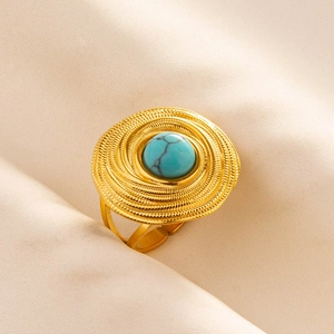 Detailed view of a gold boho ring with a turquoise stone on beige textured fabric