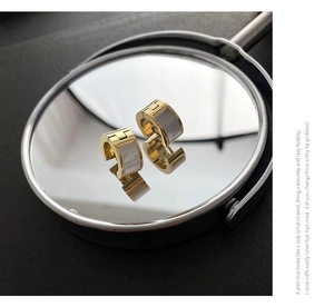 Detailed macro view of 18K gold earrings with mother of pearl inlay on mirror surface