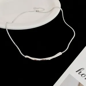 Minimalistische silberne Schlangenkette mit stromlinienförmigem Bogenanhänger auf Keramik